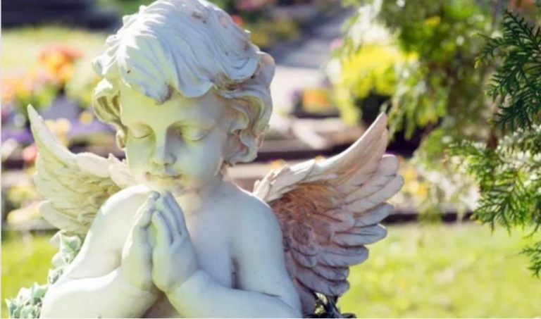 A stone Cherub praying in a garden