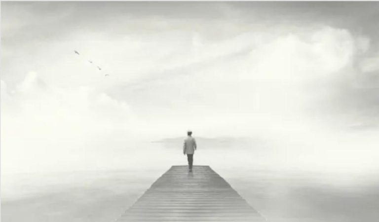 A man walking on a boardwalk in fog