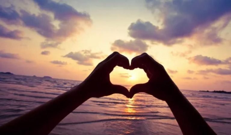 hand shaped into a love heart facing the sky