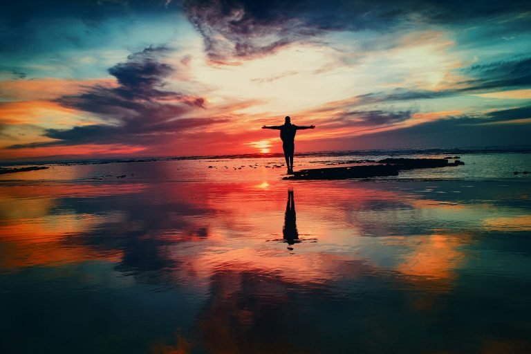 standing by a river with multicoloured sky